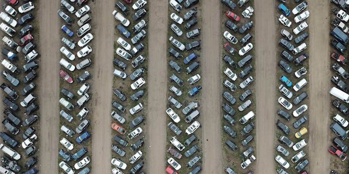 Crowded parking lot with rows of cars in front of a large building.