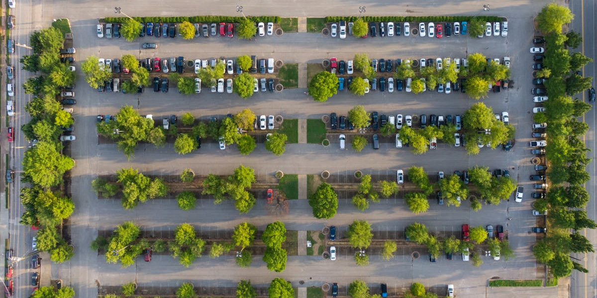 Aerial view of a half-full parking lot with rows of cars and some empty spaces scattered.